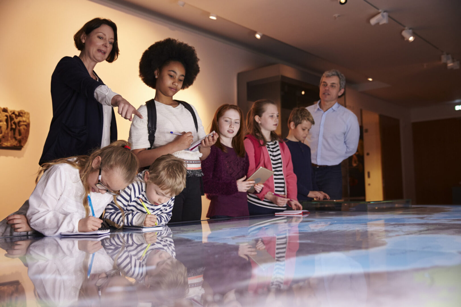 Pupils On Trip To Museum Looking At Map And Making Notes